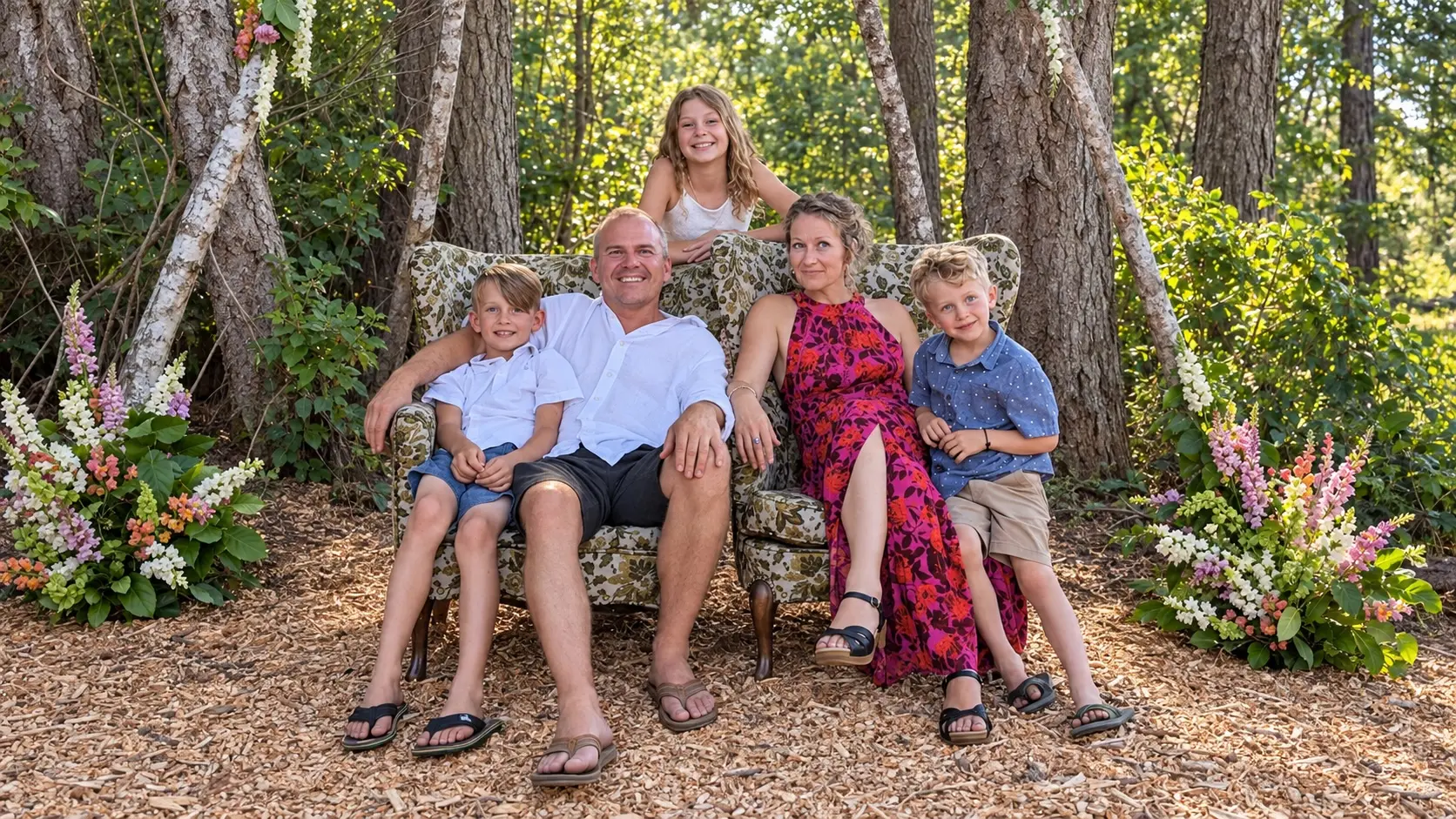 Sunny Morgan and family on a floral sofa in the woods, with lupines on both sides